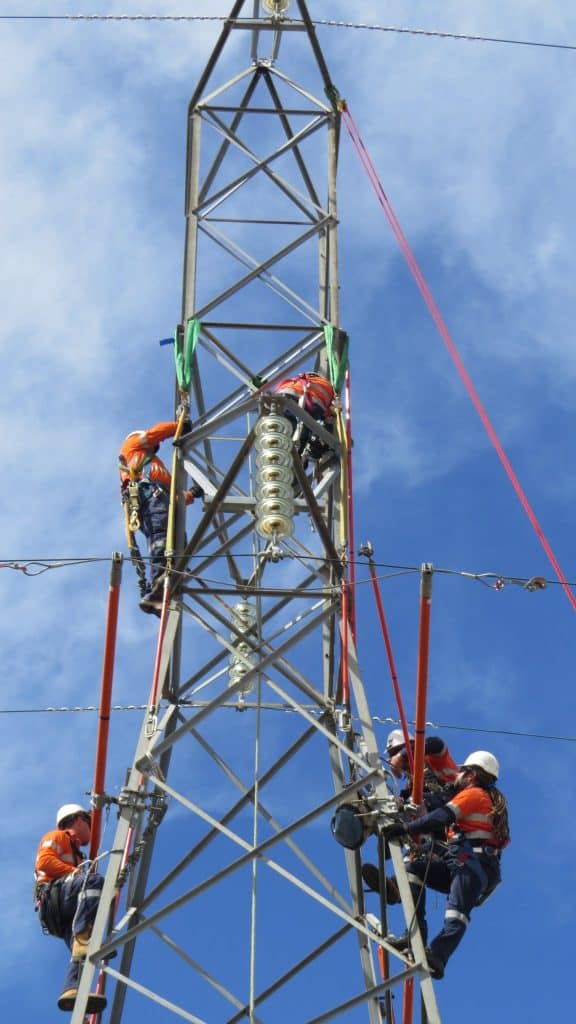 linesmen working on power pylons with operating poles